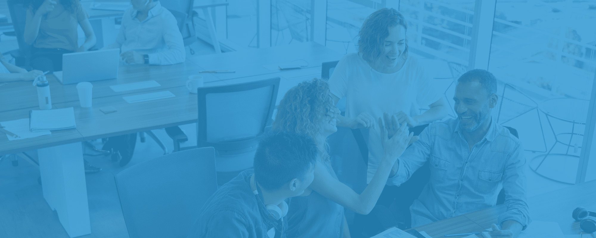 Blue image with four people smiling in an office
